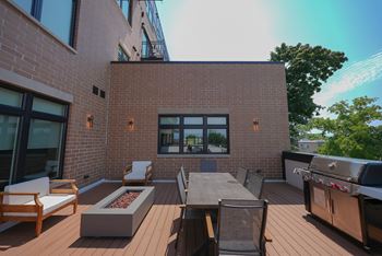 A patio with a table, chairs, and a grill.